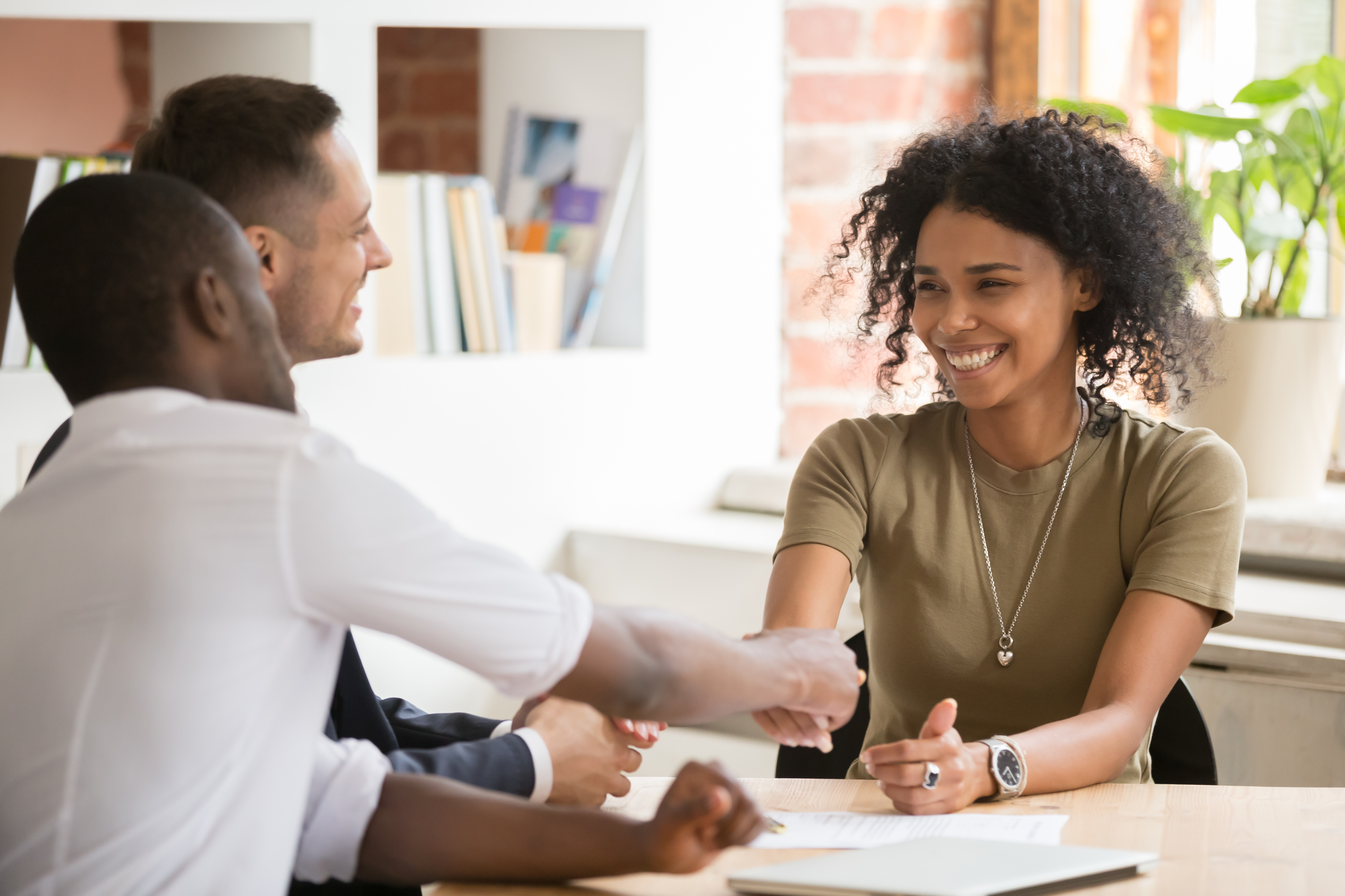 Woman shaking hands with two men in an office setting