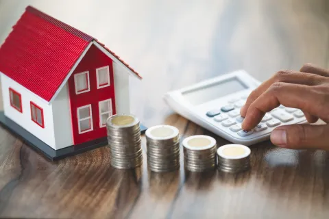 miniature building, calculator, and stacks of coins