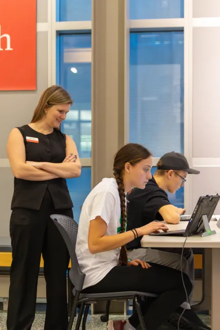 youth working on computers while a mentor looks on
