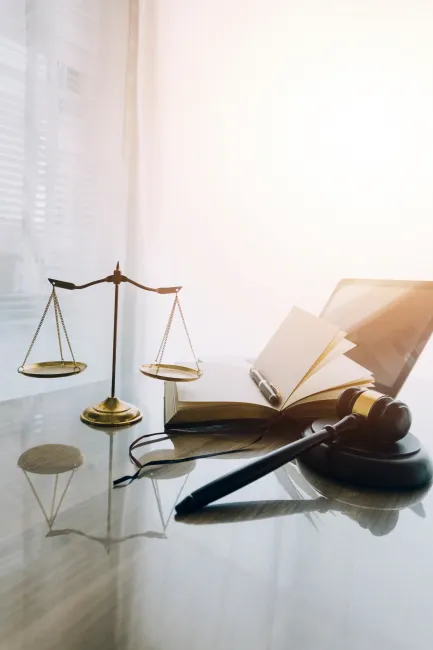 Law books and scales of justice on desk in library of law firm.