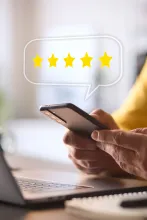 Man Using Mobile Phone With Graphic Overlay To Leave Positive 5 Star Online Review