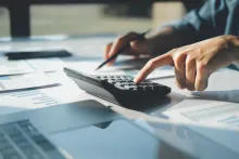 Accountant using calculator to calculate finance report in office.